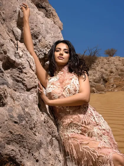 A duplicate of image 15, this image shows the full scope of a dramatic desert fashion shoot, where the gown's texture mimics the surrounding environment.
