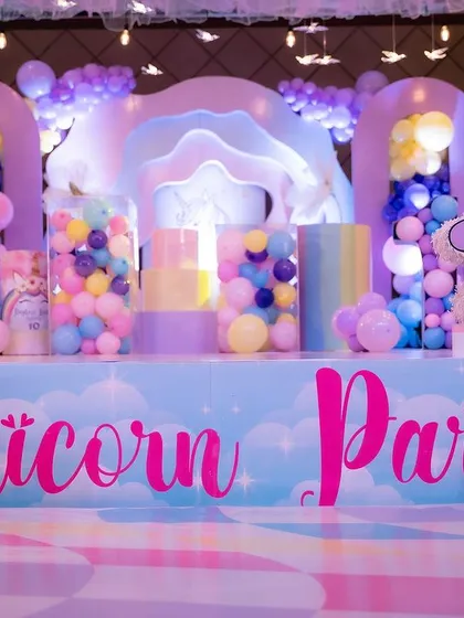 The front of the unicorn party stage, with custom lettering and colorful props.
