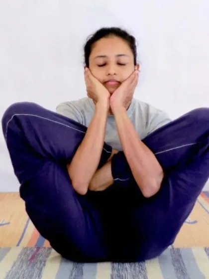 A student practices Garbha Pindasana (Embryo in Womb Pose), an advanced posture from the Ashtanga tradition that requires significant flexibility and core control.