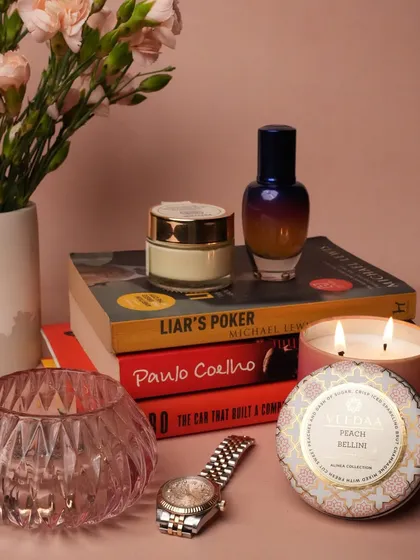 A quiet moment of luxury. This image styles our Peach Bellini candle and other personal items on a stack of books, showing how our products seamlessly blend into your daily life and personal space.