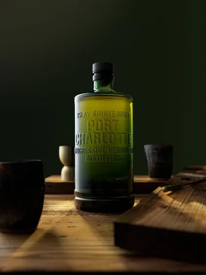 This Port Charlotte shot took two days of lighting and six different set designs to perfect. The final image uses a single sliver of light to mimic a sunbeam cutting through a dark, moody room, highlighting the bottle's green glass and embossed text.