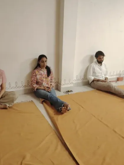 Seekers meditating along the wall during an Amavasya night. Even when the main hall is full, every corner of the space is used for sadhana.