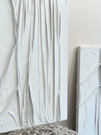 A pair of white-on-white artworks that explore texture through draped and folded fabric. These pieces have a very clean and architectural feel.