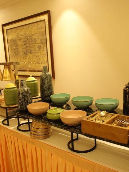 My buffet setups include more than just food. Here you can see a beautifully arranged section with colourful ceramic bowls, cutlery, and decorative vases, adding a touch of artistry to the presentation.