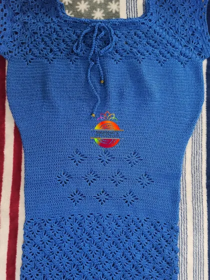 A beautiful custom-made top in a rich blue color. This piece features multiple stitch patterns, including a lacy yoke with a tie-up detail and a textured pattern on the lower body.