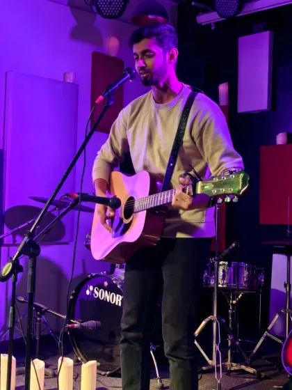 A musician performing a solo acoustic set. This image shows our standard setup with professional sound equipment, ensuring every note is heard clearly.