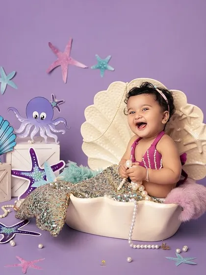 The happiest little mermaid in the sea! Her joyful laugh is infectious as she plays with a string of pearls in her magical seashell home.