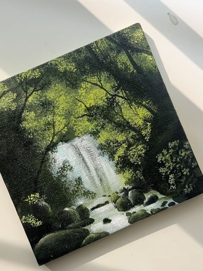 The mini waterfall painting in the sunlight, highlighting the bright greens and the texture of the canvas.