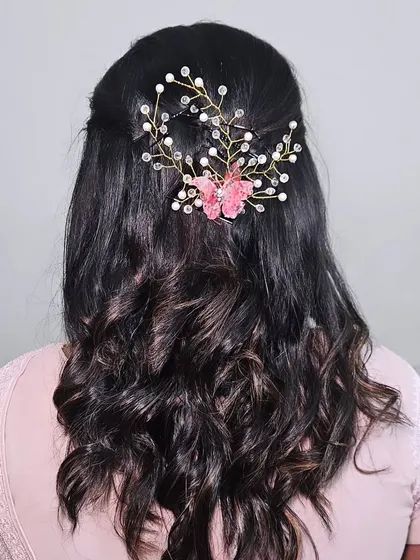 A close-up of a reception hairstyle, featuring soft curls and a delicate butterfly hair accessory.