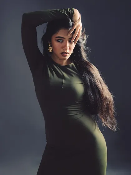 A powerful and slightly mysterious pose. The hand gesture draws attention directly to the model's expressive eyes.