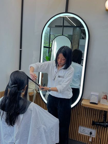 One of our talented stylists performing a precision cut, reflected in our modern, illuminated mirrors.