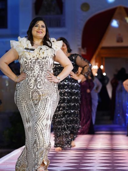A white and gold embroidered plus-size gown with dramatic ruffled shoulders. A true statement piece.