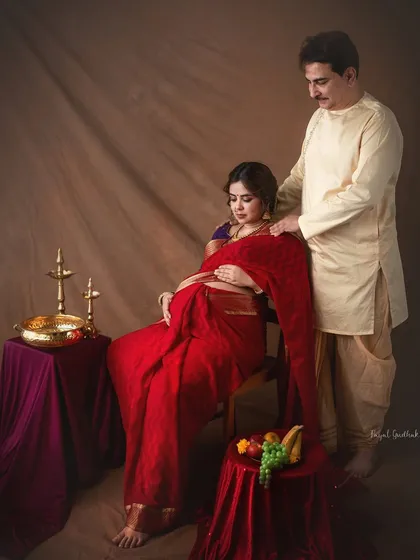 A tender moment of care as the husband-to-be adjusts his wife's saree, captured in our classic studio setup with antique props.