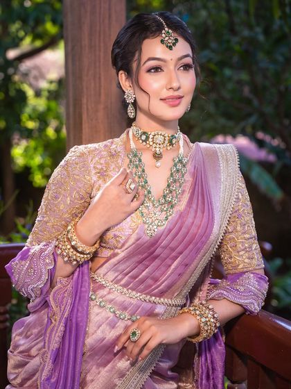 This pose highlights the delicate hand-embroidered details on the blouse and the flawless finish of the makeup.