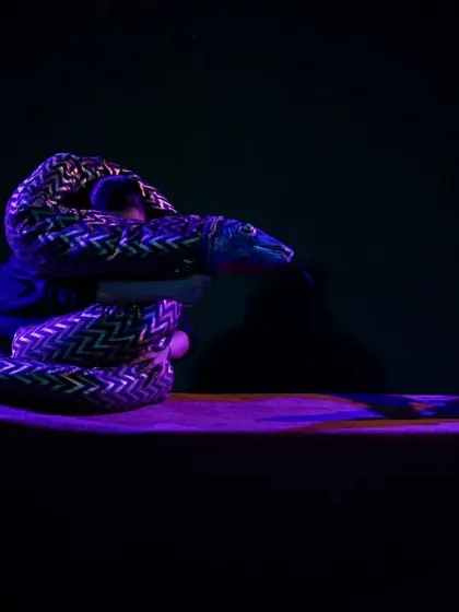 A dramatic, low-light scene from 'Be Yourself' where the snake puppet creates a moment of suspense. The lighting plays a crucial role in setting the mood for our performances.