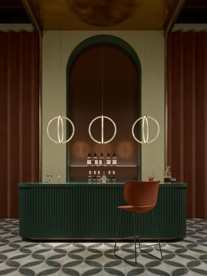A trio of Luminora pendants hangs above a stylish green bar, their circular forms echoing the archway behind them. This image shows how the lights can be used to create rhythm and harmony in a commercial interior.