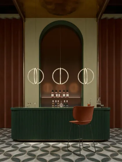 Three Luminora pendants hang over a stylish bar, their geometric form complementing the archway and ribbed details of the counter. This fixture blends simplicity, complexity, and elegance.