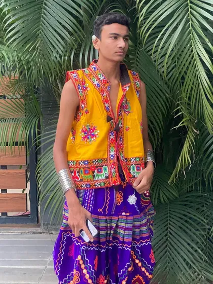 A classic look for men and boys. This yellow embroidered jacket paired with purple dhoti pants is a vibrant and festive choice for any Garba night.