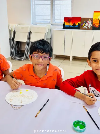 Three young boys focused on painting their nameplates, a great activity for a group of friends.