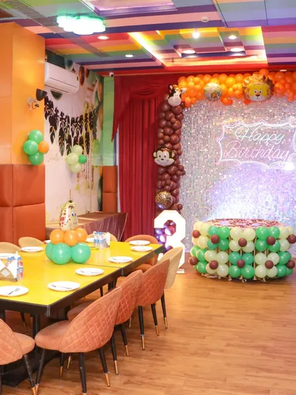 A wide view of our private party zone decorated for a jungle theme. You can see the dedicated dining tables set up next to the decorated stage area, ensuring guests are comfortable.