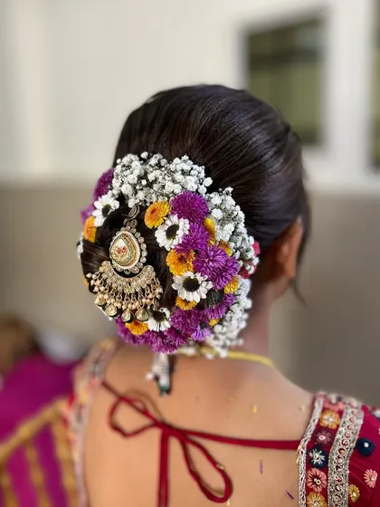 This floral bun is a work of art. I used a mix of colorful flowers and a traditional jhoomar accessory to create a unique and vibrant look for the bride's big day.