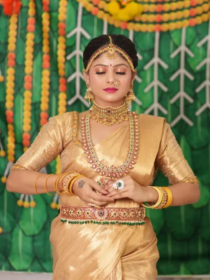 The bride's pose highlights the intricate design of the long haram and the matching waist belt.