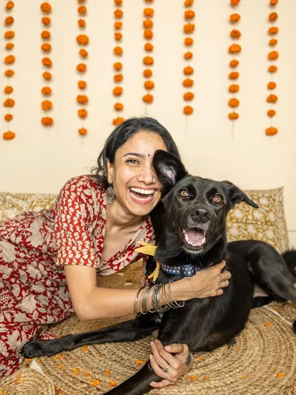 A woman shares a moment of pure joy and laughter with her black Indie dog during a Rakhi mini-shoot, capturing their happy and energetic connection.