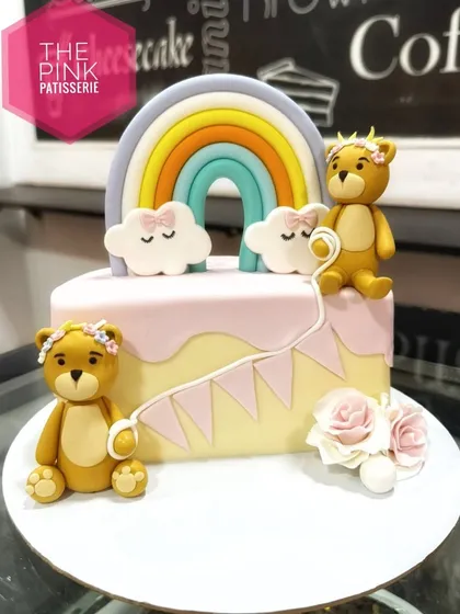 Another view of our popular teddy bear and rainbow cake. This angle shows the handcrafted fondant bears and the soft, pastel-colored rainbow.