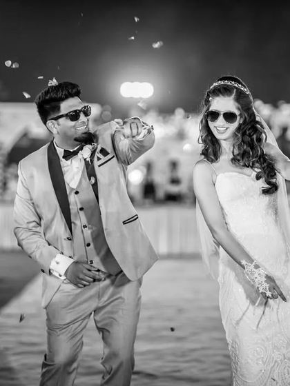 A black and white shot capturing the groom pointing at the camera during their energetic entrance. It's a fun, interactive moment with their guests.