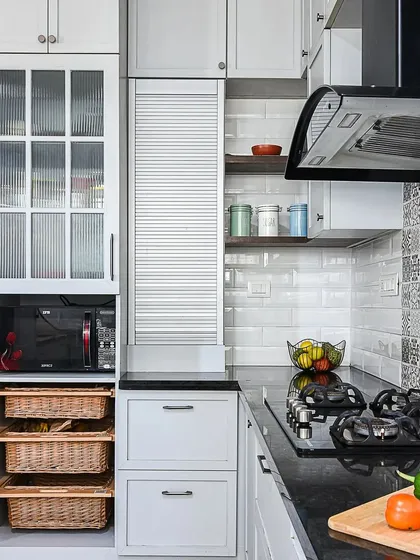 A detail shot of the classic grey kitchen, showing the wicker baskets for vegetable storage and the fluted glass cabinet for display. The patterned backsplash adds a touch of personality.