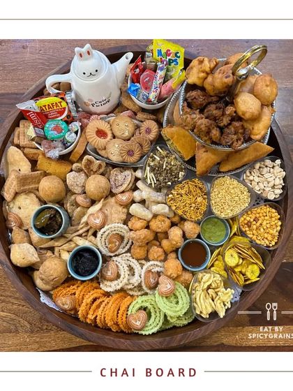 Our "Chai Board" is a nostalgic and comforting platter filled with a variety of classic Indian tea-time snacks like mathri, chakli, samosas, and biscuits.