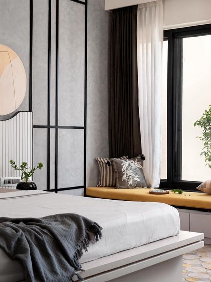 This angle shows the full layout of the master bedroom, including the cozy bay window seating with a pop of yellow, which contrasts beautifully with the monochrome and wood tones of the room.