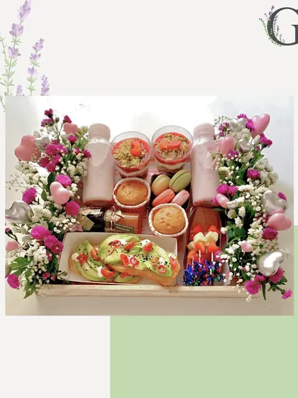 A beautiful breakfast-in-bed hamper, complete with avocado toast, muffins, macarons, parfaits, and fresh flowers. A luxurious way to start someone's special day.