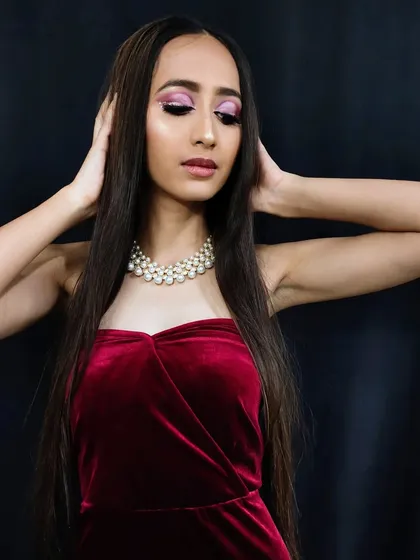 A full-body shot of the model in a velvet gown, her glamorous pink eye makeup adding a pop of color and sophistication to the overall look.