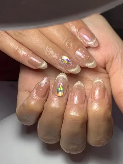 A close-up of the elegant sheer cat eye nails with a single large crystal accent.