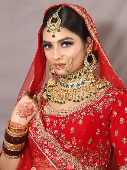 A powerful portrait of a bride in red. The makeup is bold, with strong eyes and a perfectly defined lip, creating a look of confidence.