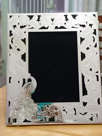 This silver frame showcases a beautiful peacock and lotus motif. The intricate cutout work is a testament to the incredible skill of the artisans I work with.