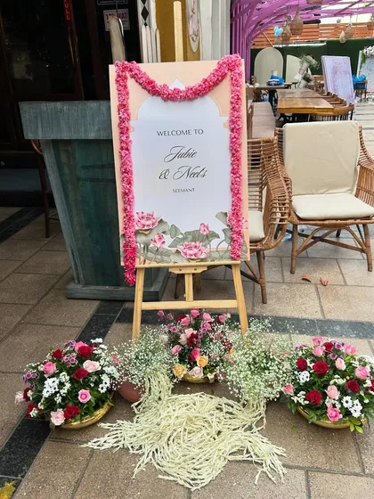 An elegant welcome easel with a custom sign, framed with a traditional marigold garland for a beautiful fusion of themes.