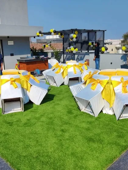 A wider angle of the rooftop party, showing how we can transform an open terrace into a functional event space with organized seating and decorations, set against the city skyline.