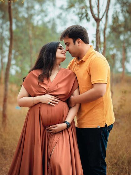 An intimate moment between a couple during their outdoor maternity shoot. The rich color of her dress stands out beautifully against the natural backdrop.
