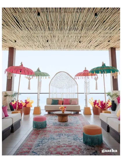 A vibrant and chic Haldi ceremony setup in Bali, featuring colorful Balinese umbrellas, custom macrame backdrops, and a stunning ocean view.