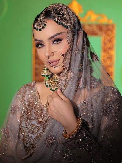 A complete bridal look with a sheer grey dupatta. The green beaded jewellery set with a traditional nath and matha patti creates a beautiful, cohesive look.