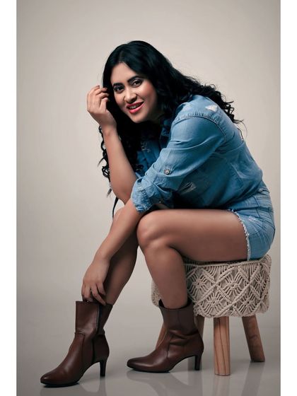 A relaxed and confident studio portrait. The denim-on-denim look and the model's easy smile create a friendly and approachable vibe.
