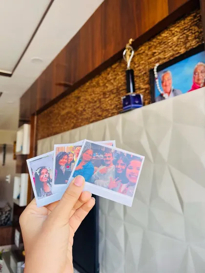 A hand holding a few Polaroid prints, showcasing memories of friends and family against a home backdrop. It’s a reminder of how these prints bring your best moments to life.