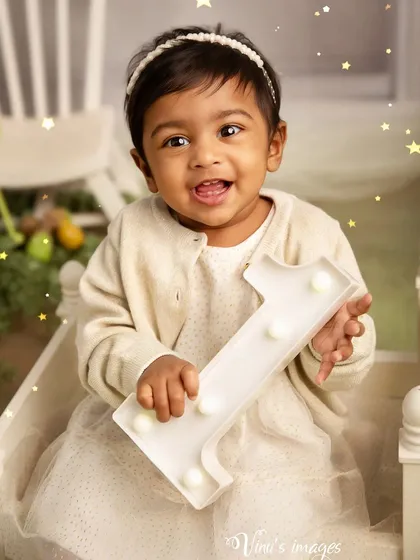 Celebrating one year of growth. This portrait captures the birthday girl holding a light-up number one, her face lit up with a happy and curious expression.