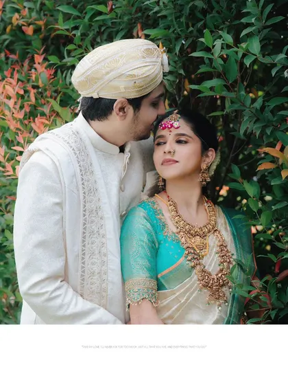 A tender moment between the bride and groom, with a gentle kiss on the forehead, captured amidst the lush greenery of an outdoor wedding venue.