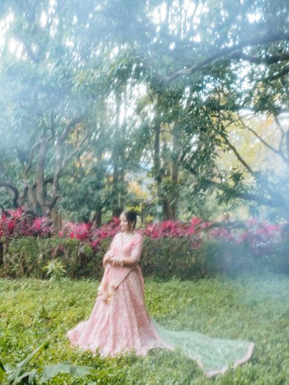A misty, romantic portrait of a bride in a garden, her long veil trailing behind her.