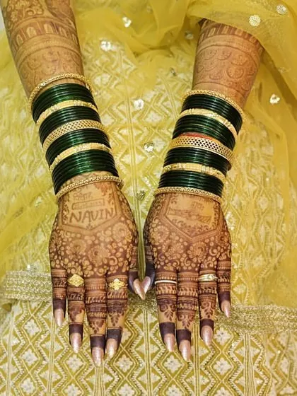 The back of the hands, showing the stunning stain of the bridal mehendi. The personalized name is clearly visible.
