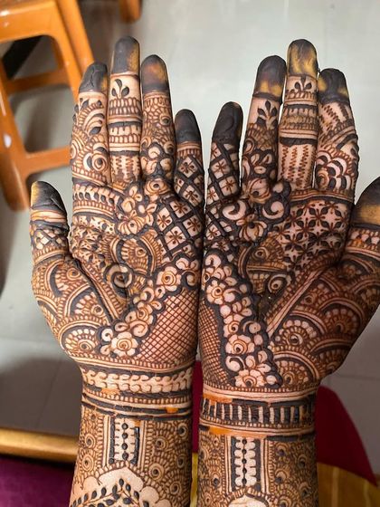 A close-up of the palms, showing the intricate floral and checkerboard patterns of this bridal design.