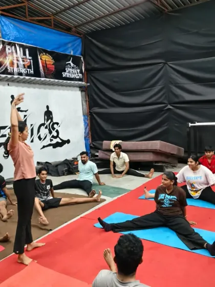 An instructor guiding the class through a wide-legged forward bend. Proper guidance is key to stretching safely and effectively.
